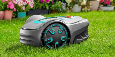 Ein Roboter-Rasenmäher mit schwarzen und blaugrünen Akzenten sitzt auf grünem Gras, mit bunten Topfblumen und Pflanzen im Hintergrund.